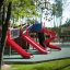 Playground structure with multiple red slides including a spiral Slide.