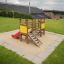 Mini play playground equipment with slide and ladders on sandy surface in open space.