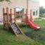 Wooden Mini play structure with red slide and climbing ramp in a backyard playground