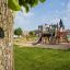 Playground Camelot castle with slide in green park.