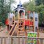Wooden Camelot castle playground with slide and climbing elements for children.