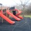 Red playground equipment with three slides, including a spiral slide.