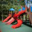 Red Slide playground equipment set with multiple slides and climbing structures in a park.