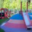 Outdoor playground with Hill Slide SL120 featuring a colorful mound and red slide.