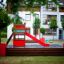 Grocer's single slide in modern playground setting with red and wooden elements.