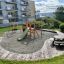 Kiosk playground equipment with slide and swings in a residential area.