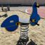 Scooter rocking playground equipment with blue and yellow design in sandy area