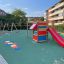 Little Jungle single slide on playground with red slide and playhouse.