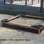 Wooden sandbox with Dino sandbox base in outdoor playground.