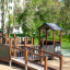 Gamma playground structure with wooden ramp and house in park setting
