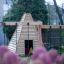 Wigwam wooden house in a playground setting with pink flowers in the foreground