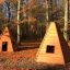 Two Wigwam wooden houses in an autumn forest clearing.