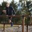 Athlete climbing over Double Jump Bars outdoor fitness equipment.