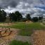Outdoor fitness park with wooden exercise equipment in a green open area.
