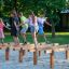 Children playing and balancing on wooden Hip Hop playground equipment outdoors.