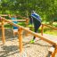 Children playing on Climb Obstacle wooden ladder in an outdoor playground.