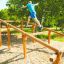 Person using Climb Obstacle wooden ladder in outdoor park.