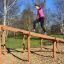 Woman climbing Climb Obstacle wooden ladder in a park.