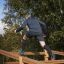 Man climbing the Climb Obstacle wooden ladder in an outdoor park.