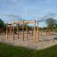 Horizontal Ladder Large wooden playground climbing structure on sand surface.