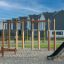 Horizontal Ladder Large wooden climbing structure on playground with sand surface and residential ho