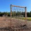 V-shape Net Large climbing net in an outdoor play area with wood chip ground.