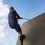 Man climbing the Climbing Ramp steel structure using a rope.