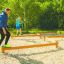 Adults and children balancing on the Balance outdoor fitness equipment.
