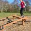 Woman balancing on Easy Balancer outdoor playground equipment.