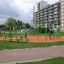 Urban playground with green and orange single swing sets surrounded by modern apartments