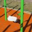 Single swing with green metal frame and white seat on an orange playground surface.