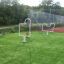 Outdoor Aim Practice II equipment on a grassy area next to a fenced sports court.