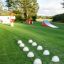 Playground equipment including a slide and tunnel system on a green lawn.