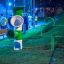 Green and white Ball catcher playground equipment in a park at night.