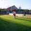 Ball catcher on a green playground with fencing and a building in the background.