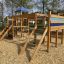 Romping Center single slide wooden playground structure with ladder and climbing net in park