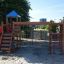 Wooden Romping Center single slide playground with climbing nets and ladders.