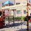 Wooden Romping Center single slide with blue net and playground structure on gravel.