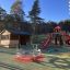 Twister castle with slide in a playground with surrounding trees and a shelter