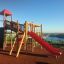 Twister castle with slide in a playground with sea view in the background.