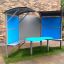Shelter with table for outdoor seating with blue panels.