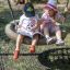 Two children sitting on a Double Swing (BNS 90cm) reading a book.