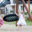 Two girls playing on a Double Swing (BNS 90cm) in a playground.