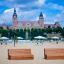 Wooden Sofa Wave benches on a sandy beach with a castle in the background.