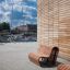Outdoor wooden benches Sofa Wave near a modern building with brick walls.