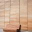Modern wooden outdoor bench in front of a wooden wall.