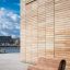 Modern wooden Sofa Wave placed in front of a contemporary building.