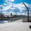 Modern outdoor Sofa Wave on a city promenade with a bridge and river in the background.