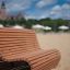 Outdoor Sofa Wave on a sandy beach with umbrellas and buildings in the background.