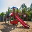 Wooden Challenger castle with slide in playground with sand surface.